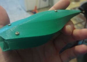 Still from the video Emergent Flow: a hand holding a green 3D-printed object