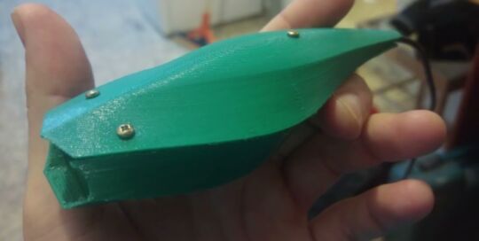 Still from the video Emergent Flow: a hand holding a green 3D-printed object