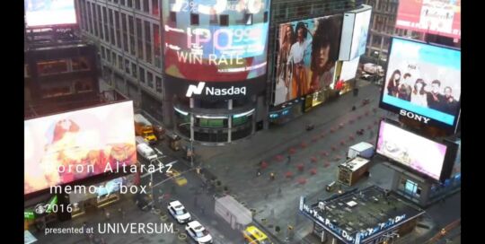 Still from the video Memory Box: a view over a busy city square with large billboards, with the title Memory Box overlaid