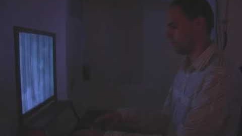 Still from a video of the Organ installation: a man seated at a keyboard in front of a glowing screen