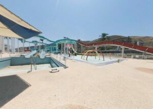 Still from a 360 tour of the closed Gai Beach Water Park in Tiberias, July 2020: an empty pool, water slides and a palm tree under a blue sky